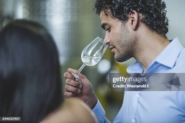 young man smelling gin at tasting in distillery - gin tasting stock pictures, royalty-free photos & images