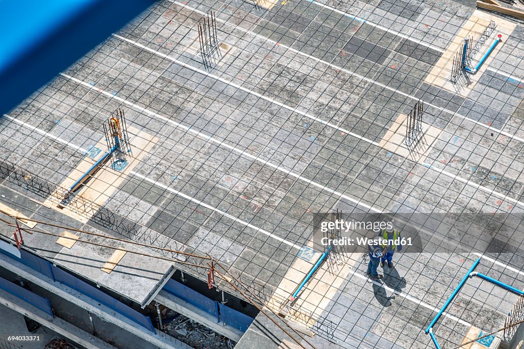 Construction workers standing on foundation, talking