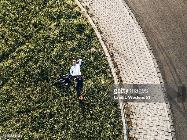 businessman lying on traffic island in roundabout - business recovery stock pictures, royalty-free photos & images