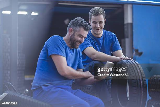 two mechanics on a break looking at cell phone - auto mechaniker stock-fotos und bilder