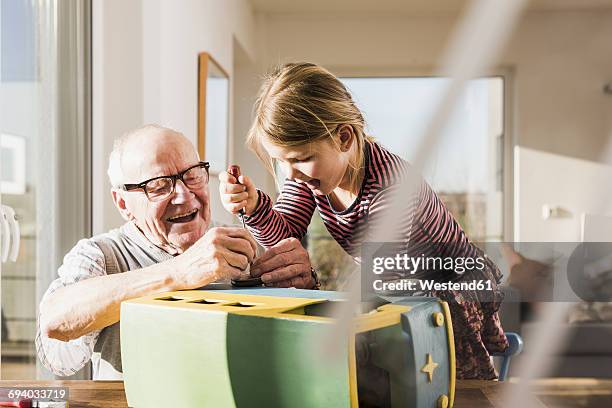 grandfather and granddaughter assembling toy bus - großvater stock-fotos und bilder