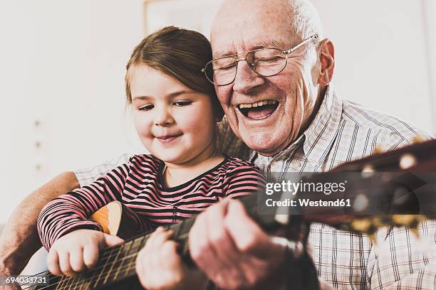 grandfather and granddaughter playing together guitar - plucking an instrument stock pictures, royalty-free photos & images