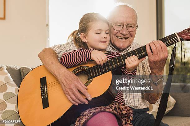 grandfather and granddaughter playing together guitar - plucking an instrument stock pictures, royalty-free photos & images