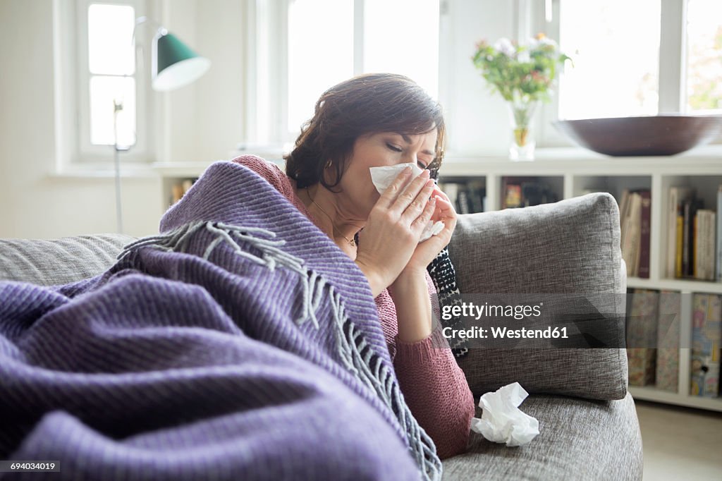 Woman having a cold lying on the sofa