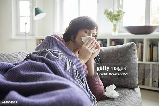 woman having a cold lying on the sofa - cold and flu 個照片及圖片檔