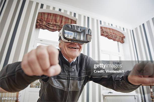 senior man in motorcycle suit wearing vr glasses - cooler opa stock-fotos und bilder