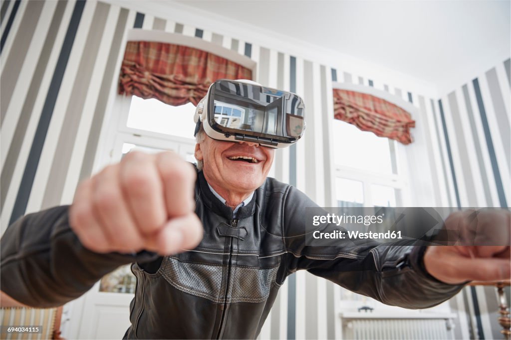 Senior man in motorcycle suit wearing VR glasses