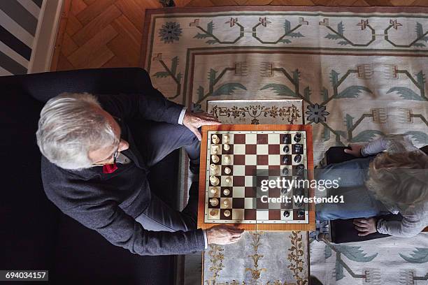 grandfather and grandson playing chess in living room - chessboard stock-fotos und bilder