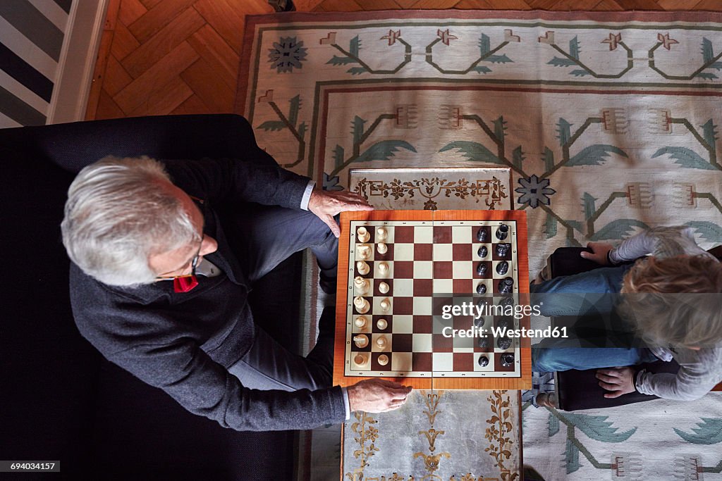 Grandfather and grandson playing chess in living room