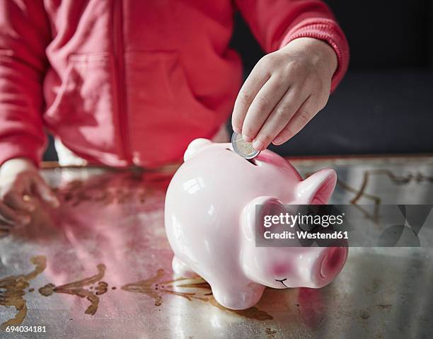 girl putting coin into piggy bank - pocket money stock pictures, royalty-free photos & images