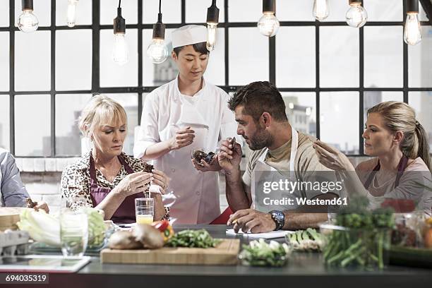 group of people taking cooking course - chef smelling food stockfoto's en -beelden