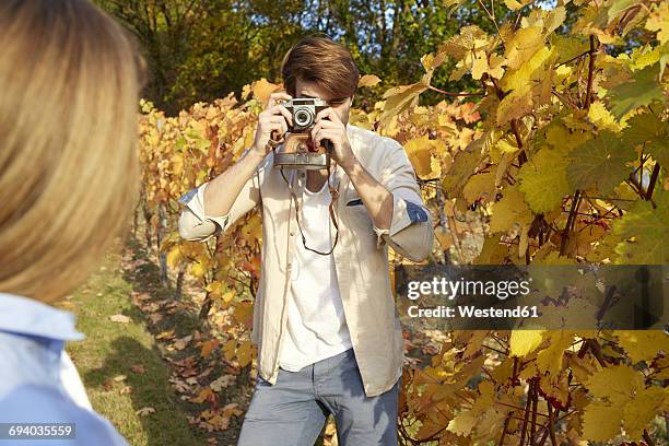 man taking picture of woman in a vineyard - heteroseksueel koppel stockfoto's en -beelden