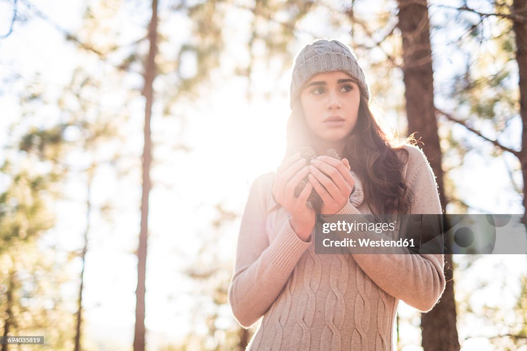 Portrait of fashionable young woman with beverage in the autumnal forest