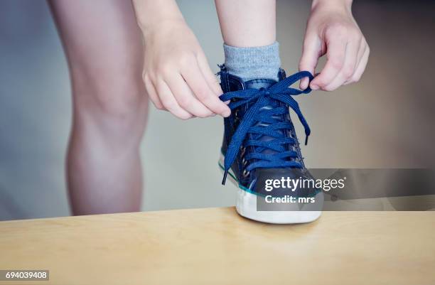 child tying shoelaces - stringa foto e immagini stock