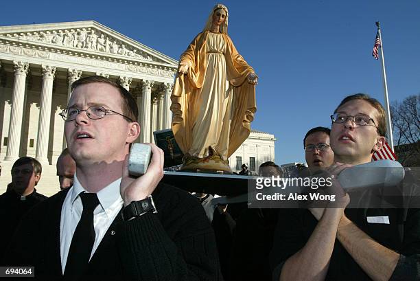 Seminarians Jeremy W. Sell and Eddie Radler of Mount Saint Marys Seminary in Emmitsburg, MD sing prayers as they hold up the statue of the Virgin...