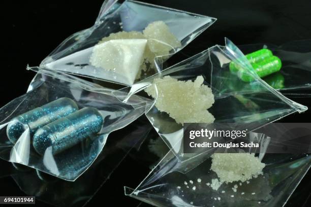 individual bags of illegal drugs on a black background - oppio fotografías e imágenes de stock