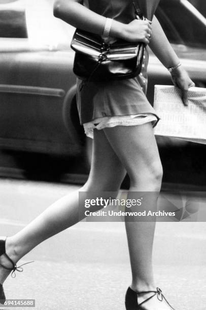 Close-up of the legs of an unidentified woman in a minidress as she walks near Central Park, New York, New York, August 1971.