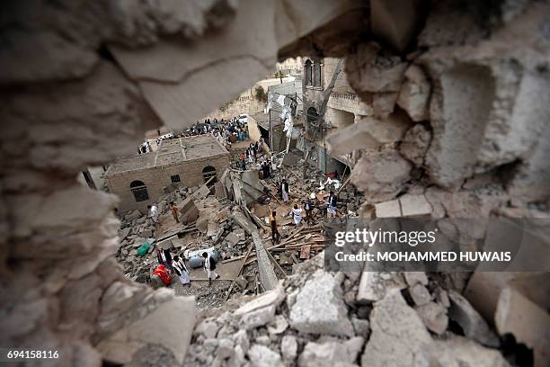 Yemenis stand on the rubble of houses destroyed in a suspected Saudi-led coalition air strike in Sanaa on June 9, 2017. Four civilians, including two...
