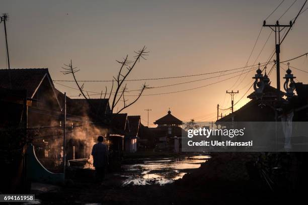 Man walks at a village sits surrounded by rising sea levels on June 6, 2017 in Pekalongan, Indonesia. Indonesia is known to be one of the largest...