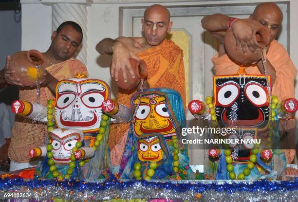 Indian Hindu devotees with the International Society of Krishna Consciousness pour water onto idols of the Hindu deity Jagannath, his brother...