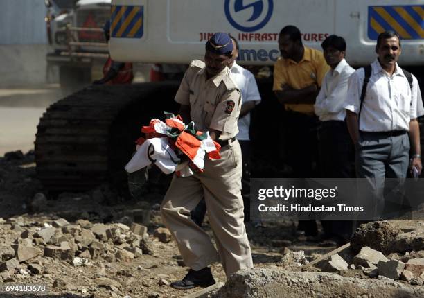 Policeman gathers abandoned flags belonging to political parties after a clash brokeout between supporters of National Congress Party and Shiv...