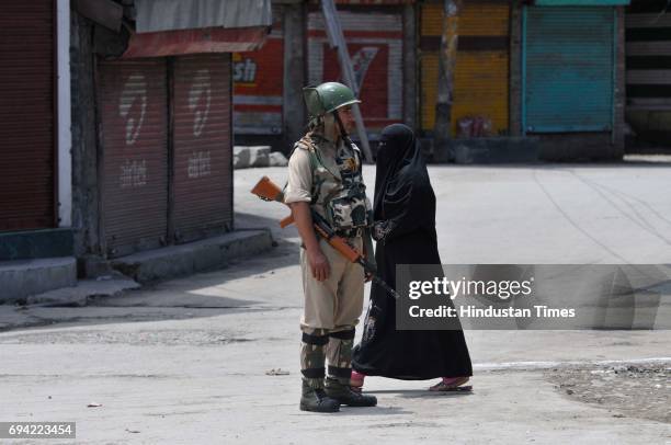 Kashmiri woman past paramilitary soldier as he stands guard during a curfew and strike on June 9, 2017 in downtown Srinagar, India. The valley's...