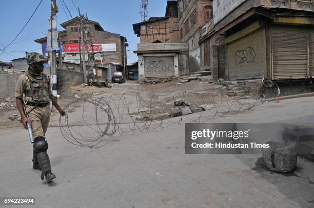 Paramilitary soldier closes the road with concertina razor wire during a curfew and strike on June 9, 2017 in downtown Srinagar, India. The valley's...