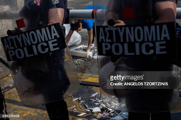 Parliament employee cleans the main entrance of the Greek parliament guarded by police officers, on June 9 after members of the Communist-affiliated...