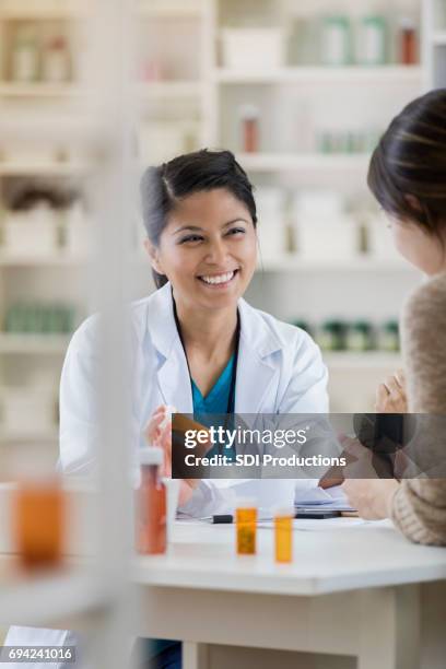 cheerful female pharmacist talks with customer - pharmacist and customer stock pictures, royalty-free photos & images