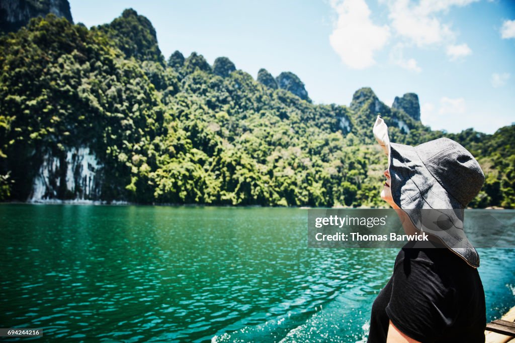 Woman on bamboo raft looking at limestone cliffs in Khao Sok National Park Thailand