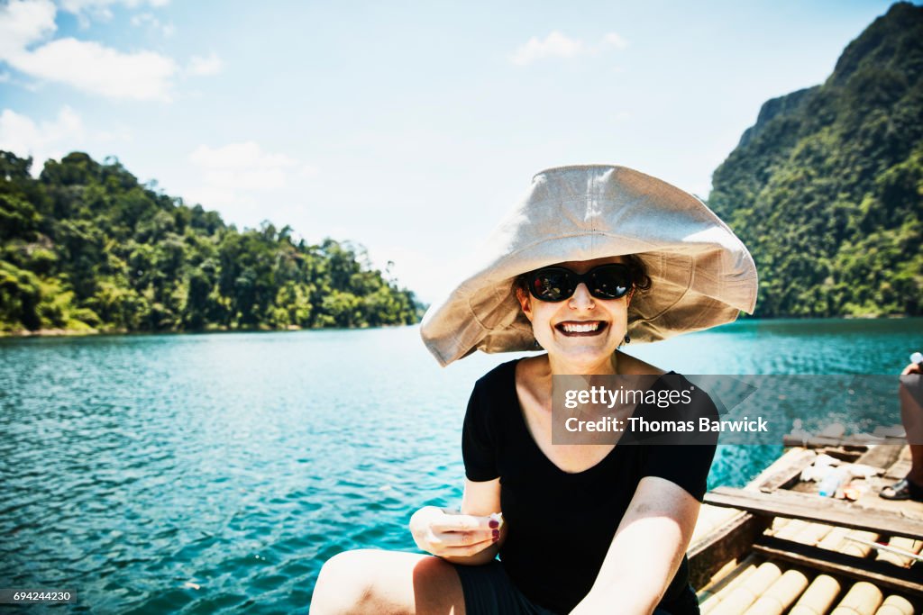 Smiling woman riding on bamboo raft in Khao Sok National Park Thailand