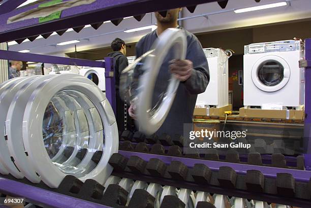 Worker prepares to attach the front door to a washing machine on an assembly line at the AEG/Electrolux factory January 24, 2002 in Nuremburg,...