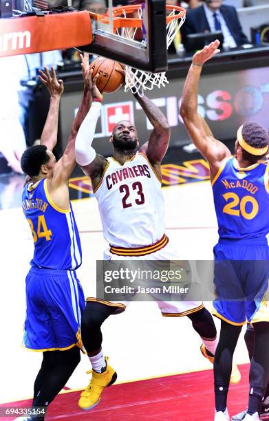 LeBron James of the Cleveland Cavaliers drives to the basket against Shaun Livingston and James Michael McAdoo of the Golden State Warriors in the...