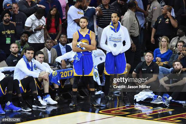 Stephen Curry and Shaun Livingston of the Golden State Warriors look on from the sideline late in the fourth quarter against the Cleveland Cavaliers...
