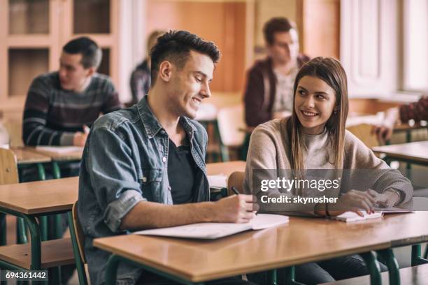 happy high school friends talking in the classroom. - teenage romance stock pictures, royalty-free photos & images