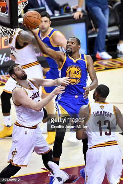 Kevin Durant of the Golden State Warriors drives to the basket against Kevin Love and Tristan Thompson of the Cleveland Cavaliers in the third...