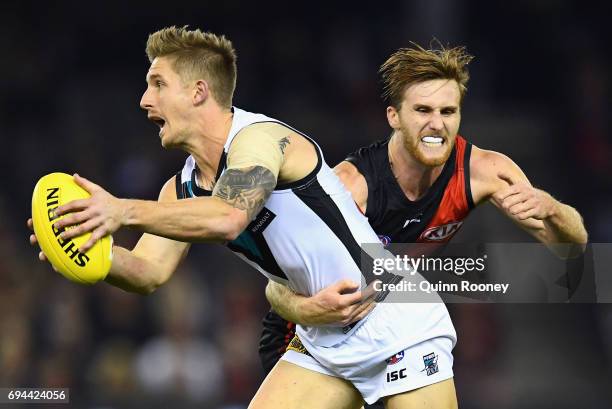 Hamish Hartlett of the Power is tackled by James Stewart of the Bombers during the round 12 AFL match between the Essendon Bombers and the Port...