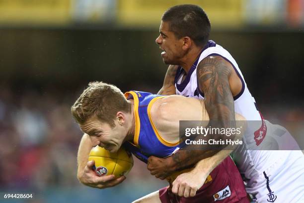 Ryan Harwood of the Lions is tackled by Bradley Hill of the Dockers during the round 12 AFL match between the Brisbane Lions and the Fremantle...