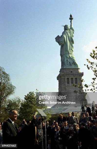 With the Statue of Liberty in the background, President Lyndon B Johnson addresses the crowds before the signing of the Immigration and Nationality...