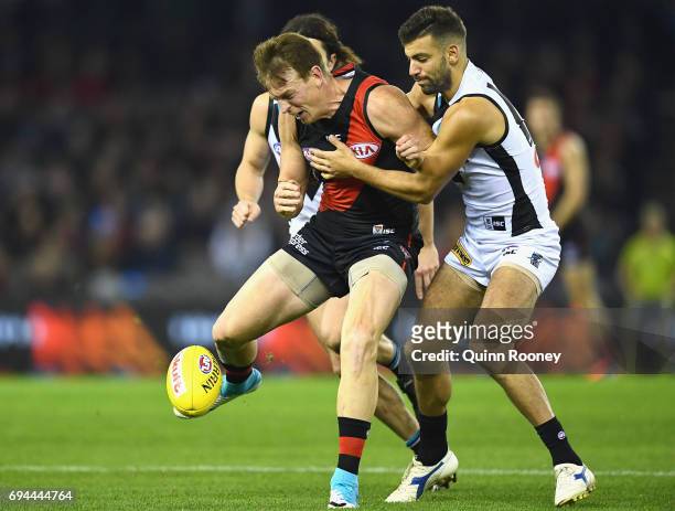 Brendon Goddard of the Bombers kicks whilst being tackled Jimmy Toumpas of the Power during the round 12 AFL match between the Essendon Bombers and...