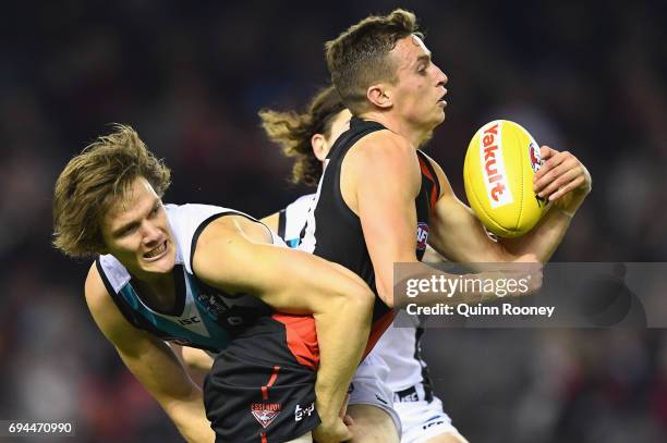 Orazio Fantasia of the Bombers handballs whilst being tackled by Jared Polec of the Power during the round 12 AFL match between the Essendon Bombers...