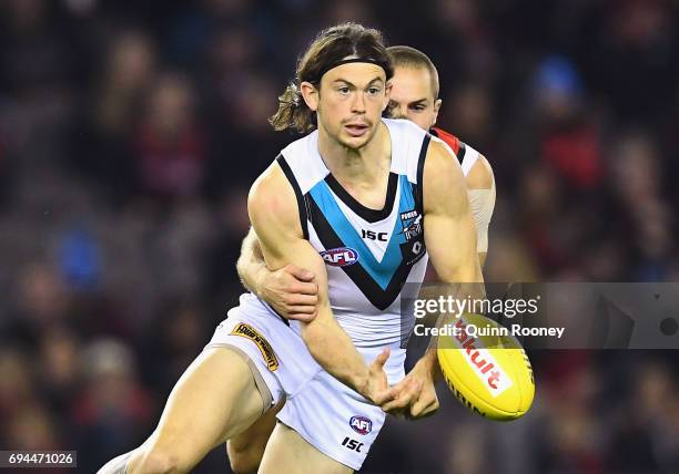 Jasper Pittard of the Power handballs whilst being tackled David Zaharakis of the Bombers during the round 12 AFL match between the Essendon Bombers...