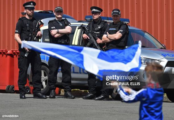 Armed police stand ready as a young Scotland fan waves The Saltire, the Scottish flag ahead of the group F World Cup qualifying football match...