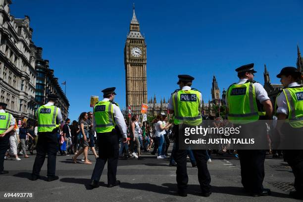 Police officers monitor as protesters with anti-Conservative Party and anti-Democratic Unionist Party placards march into Parliament Square in front...