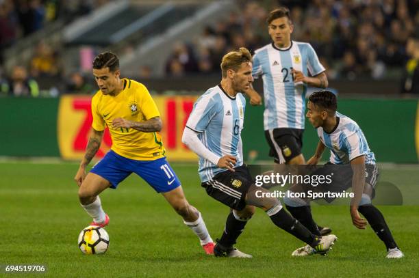 Philippe Coutinho of the Brazilian National Football Team controls the ball in front of Lucas Biglia of the Argentinan National Football Team and...