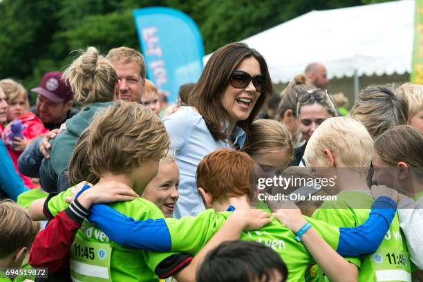 Crown Princess Mary of Denmark surrounded by kids during the warm-up exercise at the 'Children's Relay Run' in Faelledparken on June 10, 2017 in...