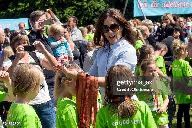 Crown Princess Mary of Denmark presents medal to a young runner having passed the finishing line at the 'Children's Relay Run' in Faelledparken on...