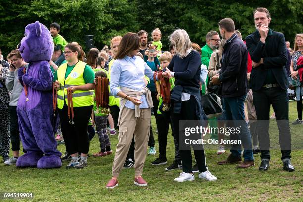 Crown Princess Mary of Denmark receives an arm's length of medals at the finishing line which she presents to the participants at the 'Children's...
