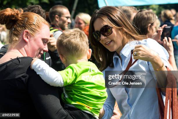 Crown Princess Mary of Denmark presents medal to a young runner having passed the finishing line at the 'Children's Relay Run' in Faelledparken on...