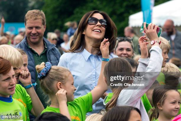Crown Princess Mary of Denmark surrounded by kids during the warm-up exercise at the 'Children's Relay Run' in Faelledparken on June 10, 2017 in...
